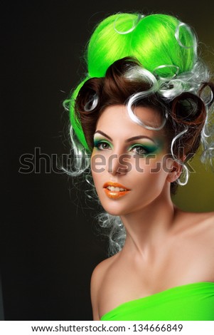 beautiful fashionable young woman with creative fantasy hairstyle with green hairs and art make up