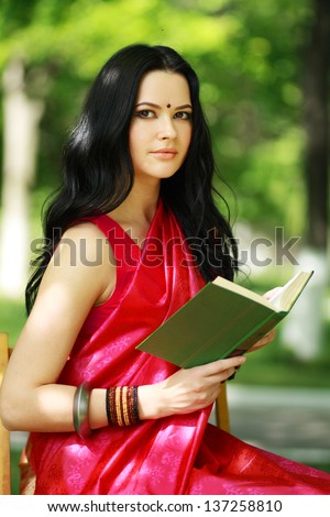 A shot of an asian or indian student in traditional clothes studying on campus park