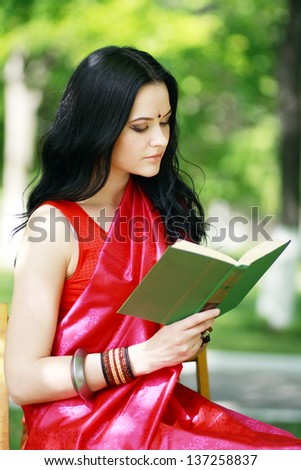 A shot of an asian or indian student in traditional clothes studying on campus park