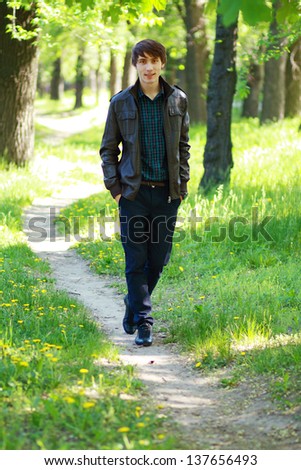 Young man walks on path in city park