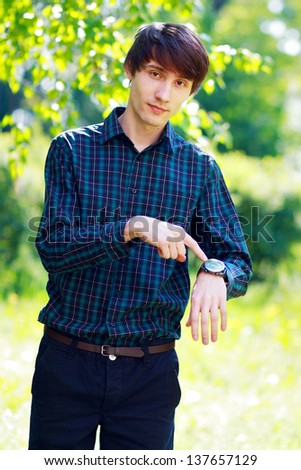 business man looking to the camera and pointing at his watch outdoor. Time to relax