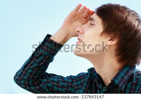 young man was looking at the sky and cover his eyes with hand