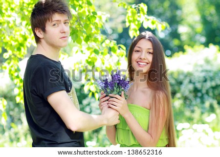 A young man presenting blue flowers to a woman on a summer day. Focus on woman face