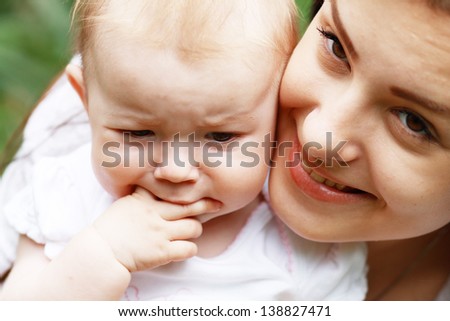 Mother trying to calm her crying unhappy baby outdoor