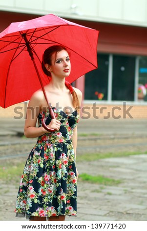 beautiful woman holding a red umbrella in the city street