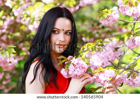 beautiful asian indian woman in the park on a warm spring day with blossom flowers around her