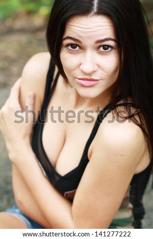 Outdoors closeup portrait of a young tanned brunette beauty with emotions on her face