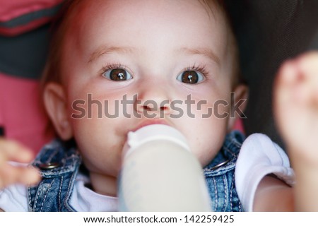 child eating out of a plastic bottle outdoor