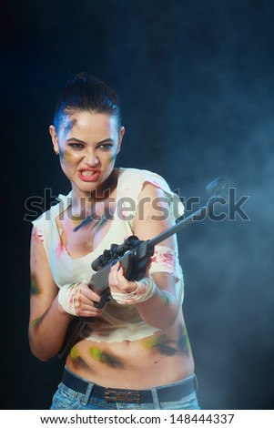 Beautiful woman holding weapon weared camo over dark background