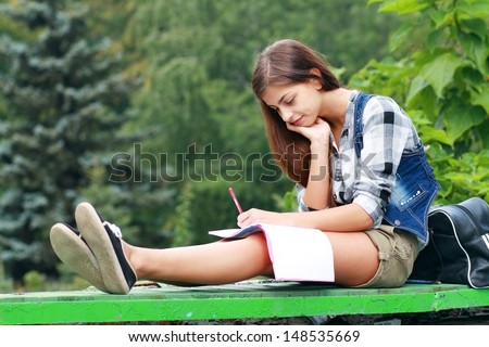 Beautiful School Or College Girl Sitting On The Bench With Book And Bag Studing In A Park