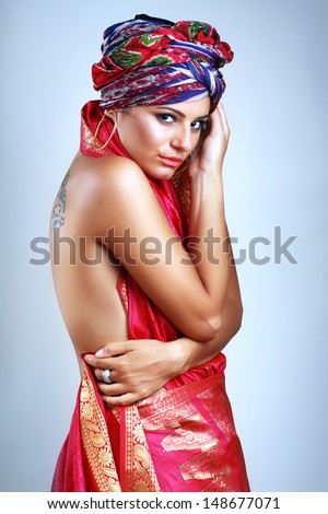 A photo of beautiful girl in a head-dress turban from the coloured fabric and red ethnic dress, glamour