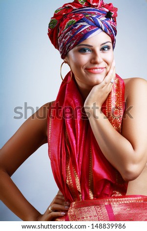 A photo of beautiful girl in a head-dress turban from the coloured fabric and red ethnic dress