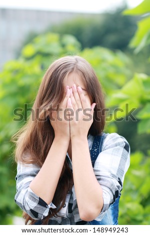 teenage girl hid her face in hands outdoor