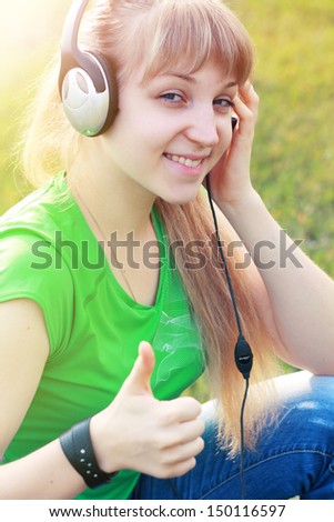 Woman listening to music. Female student girl outside in park listening to music on headphones while studying. Happy young university student
