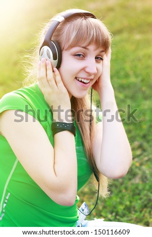 Woman listening to music. Female student girl outside in park listening to music on headphones while studying. Happy young university student