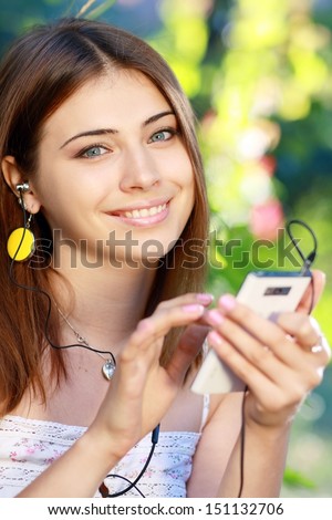 Close up portrait of a young woman using a smartphone to listen to music with her head phones