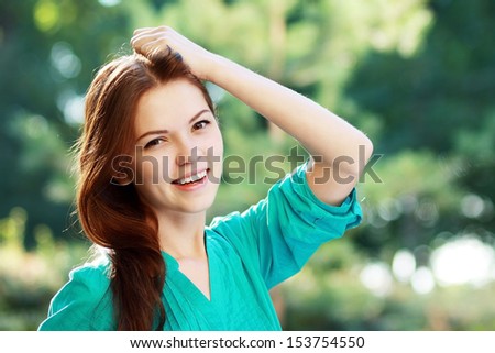 close-up portrait of beautiful young blond woman in white blouse at park holding her head enjoying fresh air