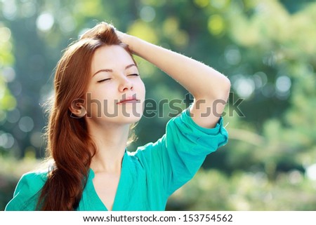 close-up portrait of beautiful young blond woman in white blouse at park holding her head enjoying fresh air
