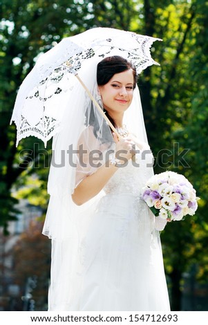 Beautiful bride with stylish make-up in white dress hold white sun umbrella