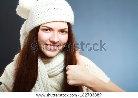 Happy young woman in winter clothes showing thumbs up copyspace