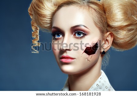 halloween broken doll beautiful girl with perfect make up and hairstyle over dark blue background