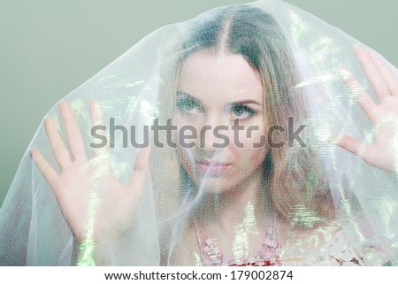 Woman under White Sheer fabric covering her trying to escape.