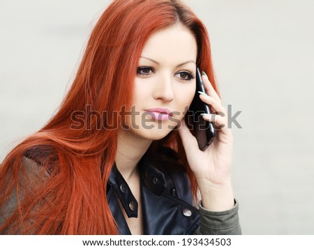 Natural portrait of a pretty young woman chatting on her mobile phone outdoors