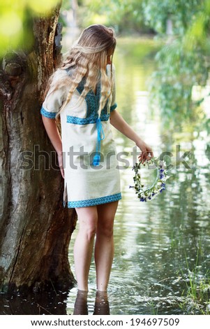 Portrait of a young girl on the bank of the river, prepared up for the holiday of Ivan Kupala (John Baptist\'s Day)