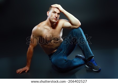 Portrait of a well built shirtless muscular male model sitting on the floor