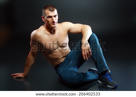 Portrait of a well built shirtless muscular male model sitting on the floor