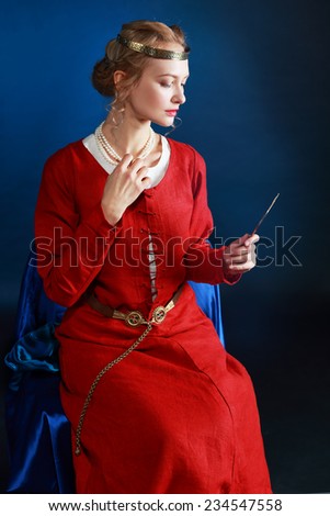 Very beautiful woman in medieval dress looking to the hand mirror look like a old time painting looks like a queen