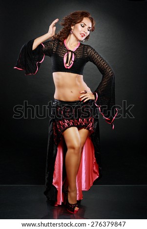 attractive woman dancing belly dance over black background