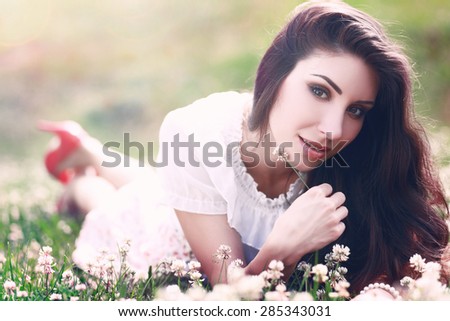 beautiful young brunette woman on the meadow with white flowers on a warm summer day fashion toning