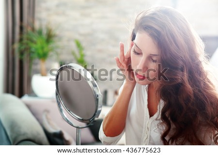 face of young beautiful healthy woman looking in the mirror