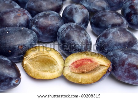 group of purple plums close up with one plum showing pulp
