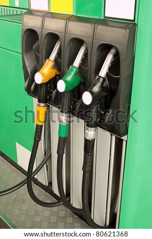 Gas nozzles at the gas station A row of 3 different gas pumps black yellow and green