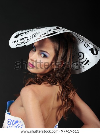 Gorgeous glamour woman close up in big white paper hat isolated over black background