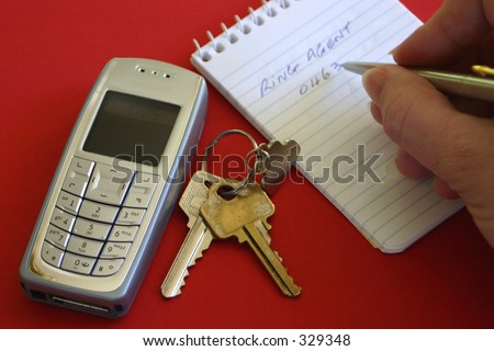 hand writing on note pad with keys and mobile cell phone