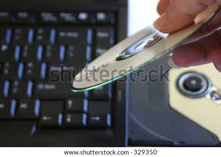 hand putting CD in laptop notebook tray