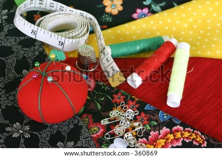 Sewing fabric with pincushion, tape measure, thimble, threads and fasteners