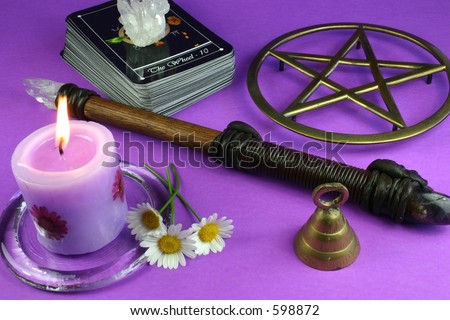Tarot cards, pentacle, crystal, candle, wand, bell and flowers