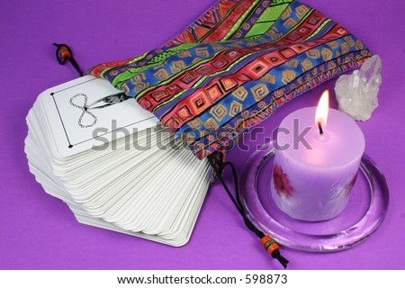 Deck of tarot cards in colorful bag with candle and crystal