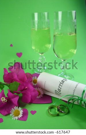 Wedding rings, marriage certificate and champagne amongst hearts and flowers
