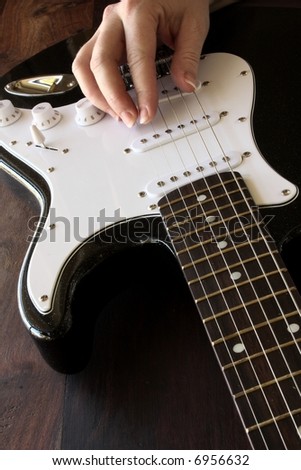 close up of black and white electric guitar with musicians hand