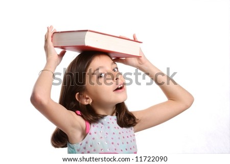 young happy girl / child balancing book on her head - against white background