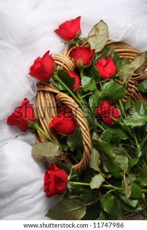 long stem red roses in wicker basket on white tulle fabric