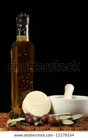 natural olive oil soap olives branch and bottle mortar and pestle against wooden mat