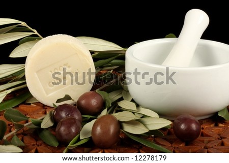 natural olive oil soap olives branch and mortar and pestle against wooden mat