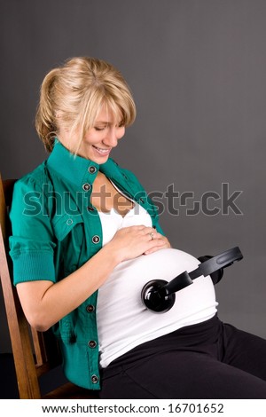 young pregnant woman with headphones on tummy with relaxing music playing for baby in womb