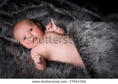 healthy young baby girl on black and grey fur rug